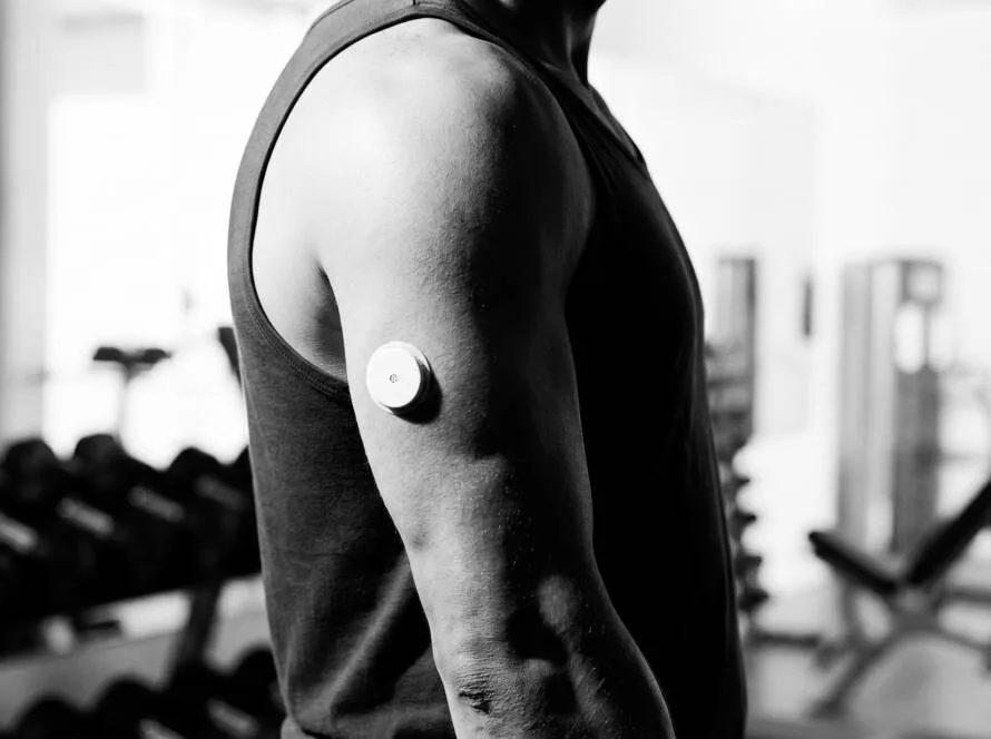 Deportista con un monitor continuo de glucosa en el brazo entrenando en el gimnasio