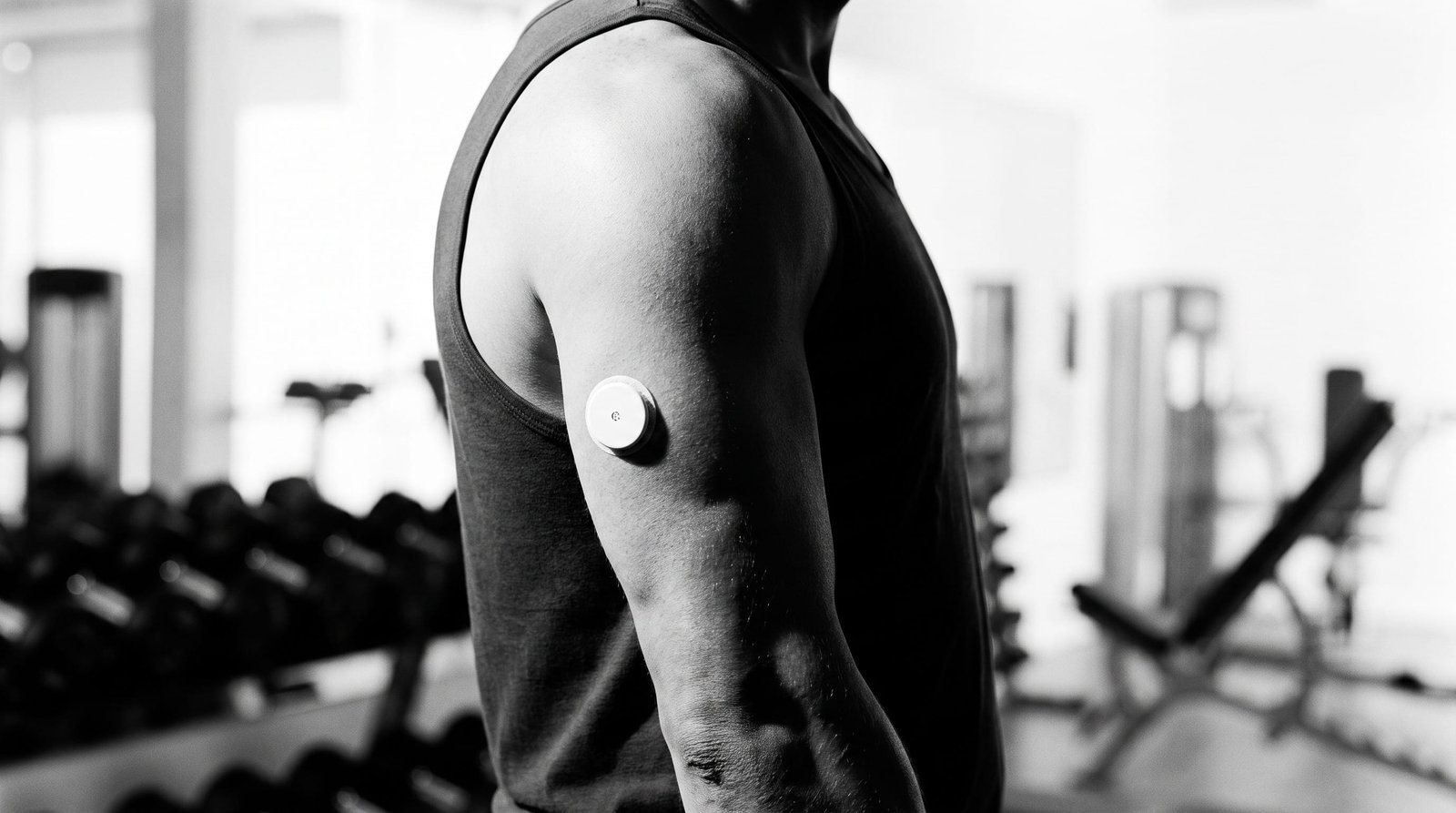 Deportista con un monitor continuo de glucosa en el brazo en el gimnasio