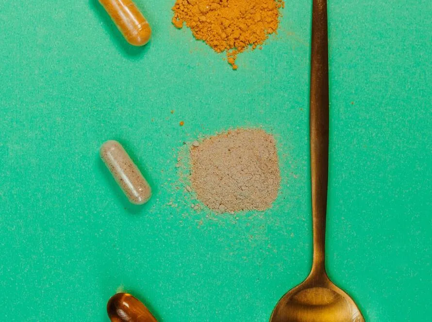 Cápsulas y polvo de suplemento sobre una cuchara, imagen ilustrativa de la suplementación con ashwagandha