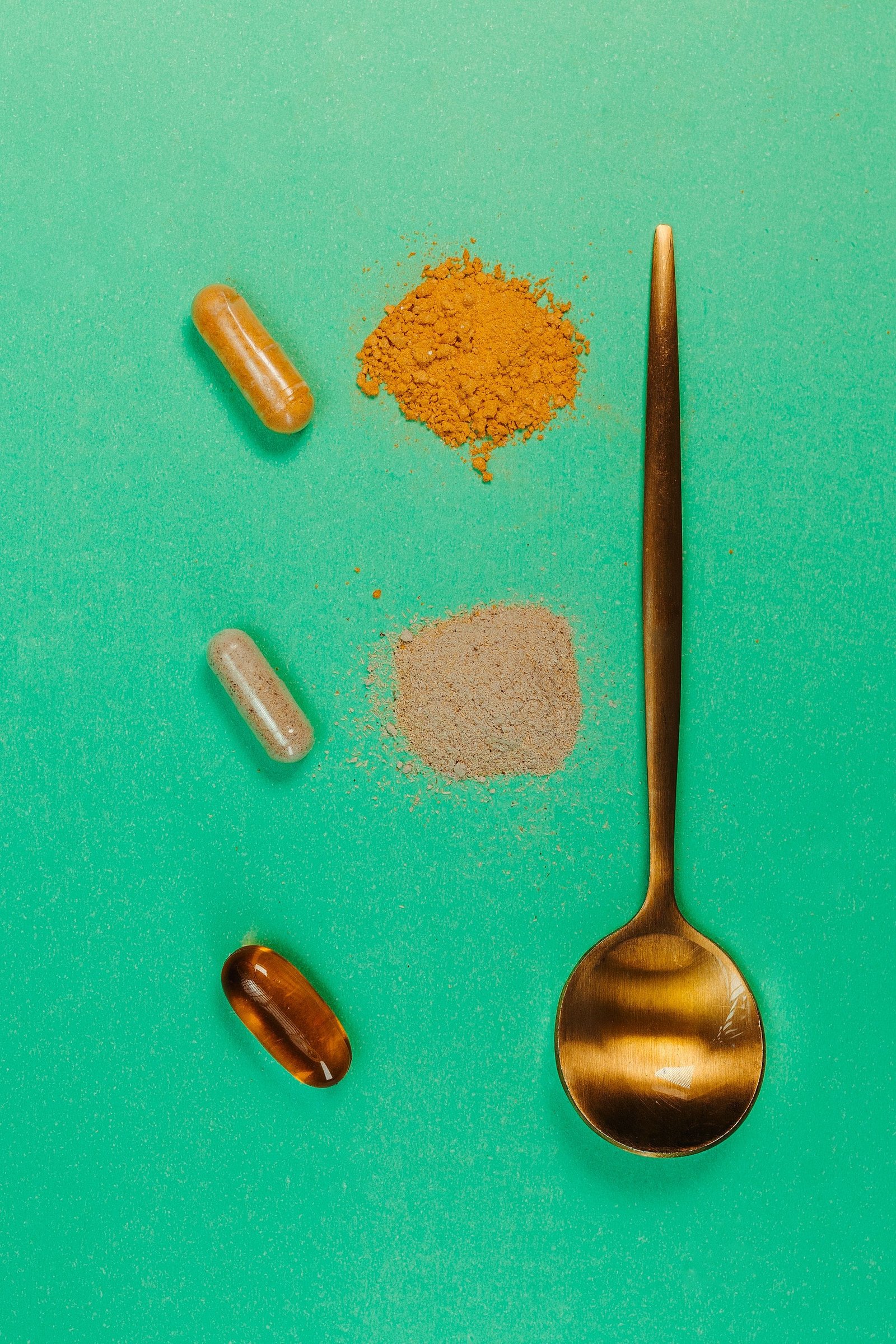Cápsulas y polvo de suplemento sobre una cuchara, imagen ilustrativa de la suplementación con ashwagandha